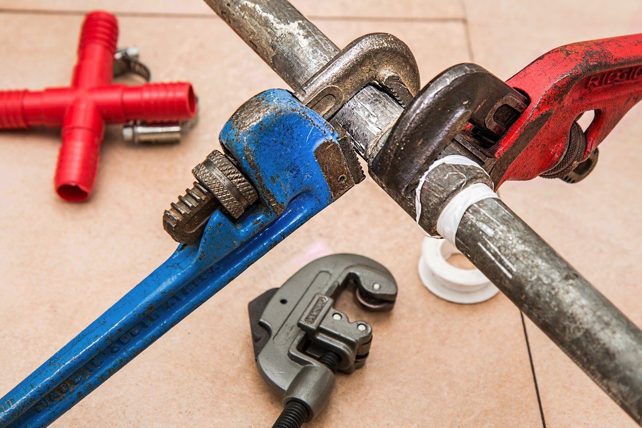 Various wrenches and other plumbing tools along a pipe arranged in an aesthetically pleasing way