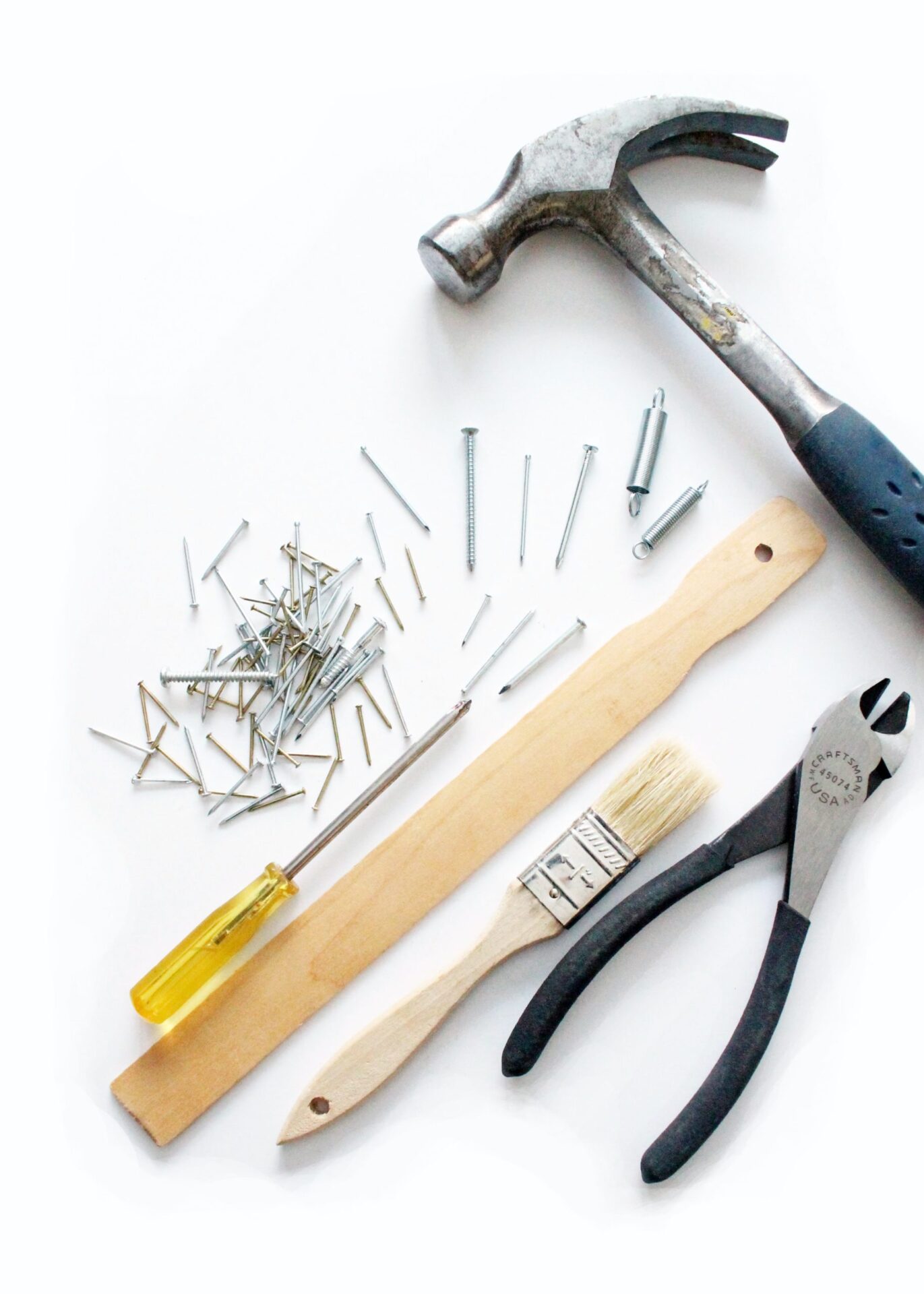 A man waring overalls and a white t-shirt using a drill to work on the electrical wiring in the ceiling